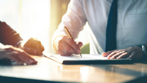 Close up of two people's hands looking over documents with a pen