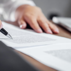 Person reviewing documents with a pen