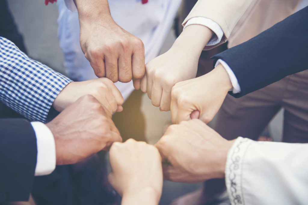 People in business attire fistbumping 