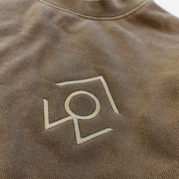 A closeup of the for people logo on a brown crewneck sweatshirt