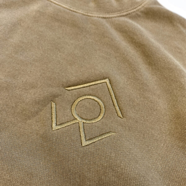 A closeup of the for people logo on a brown crewneck sweatshirt