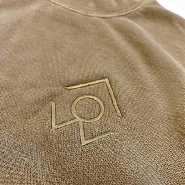 A closeup of the for people logo on a brown crewneck sweatshirt