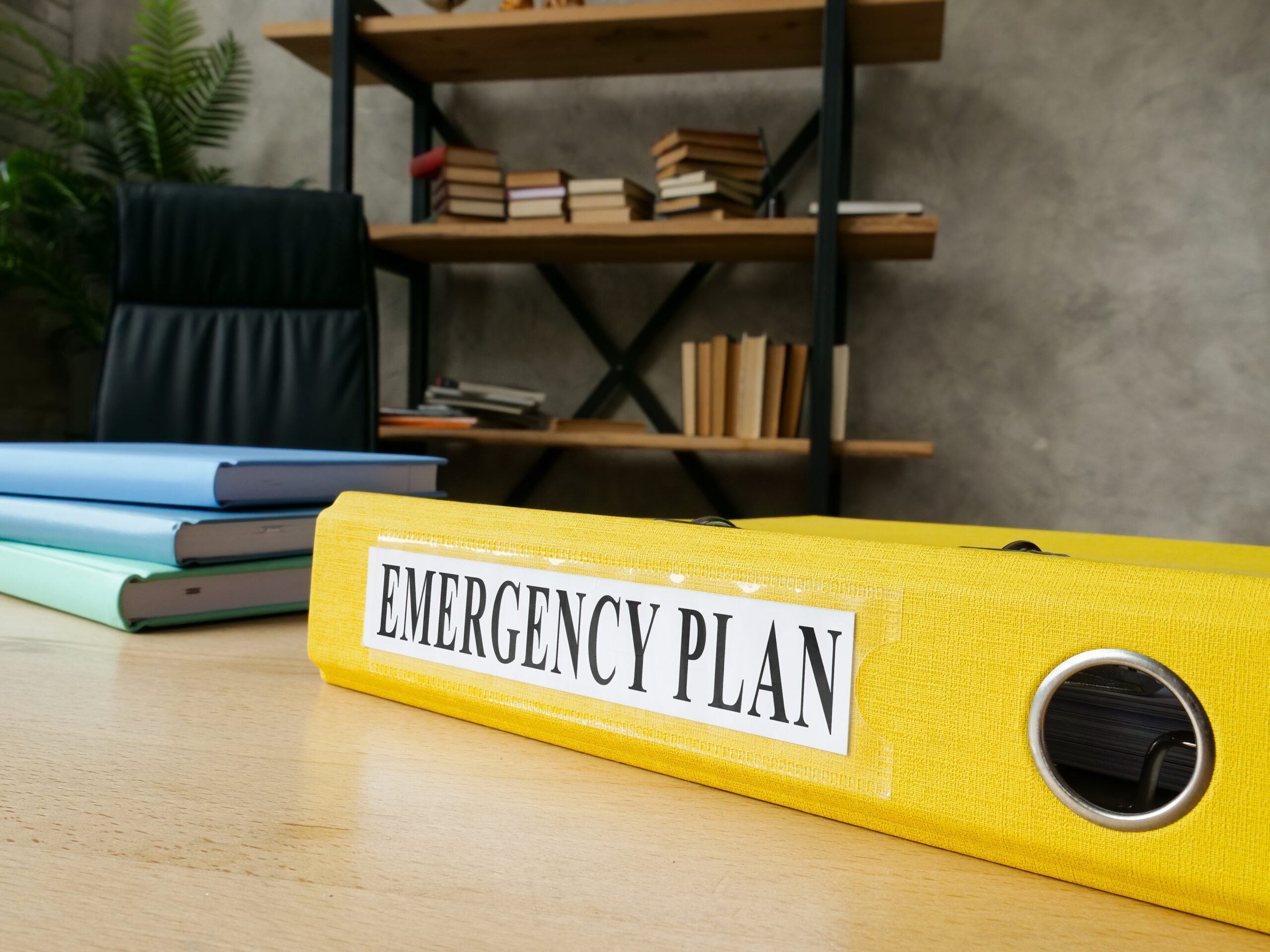 A photo of a yellow binder on a table with the label "emergency plan."
